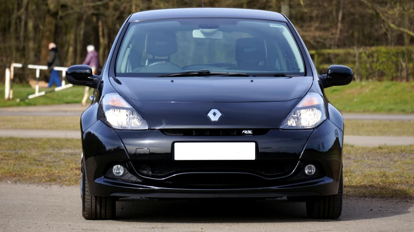 a black car with the front lights on sitting parked on a road