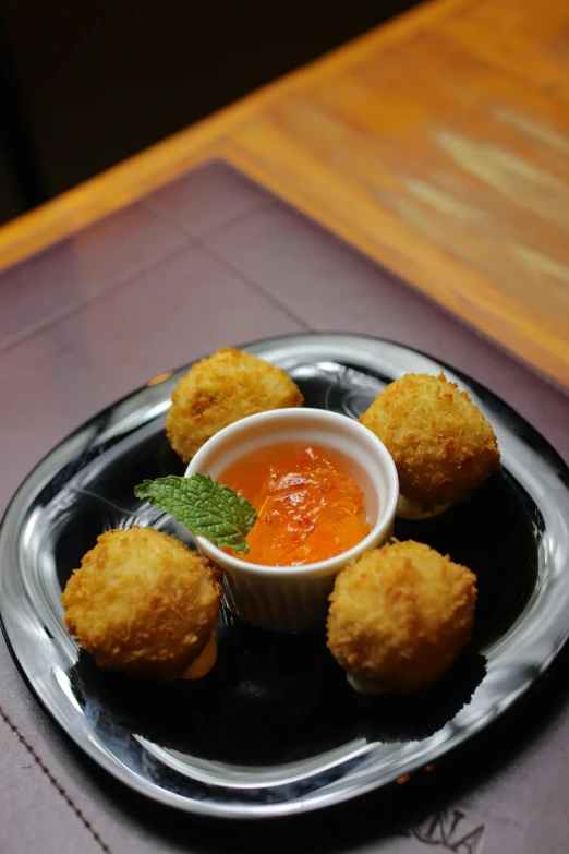 a silver plate with fried meat balls and dip