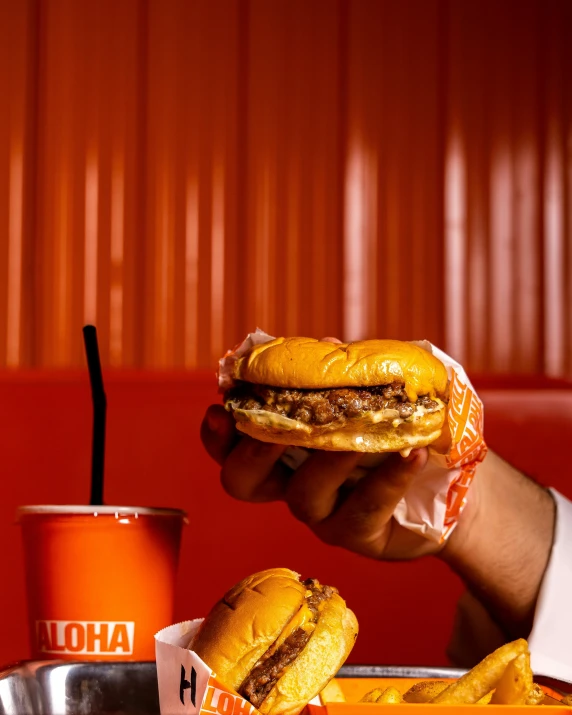 a person that is holding a sandwich in front of a tray of food