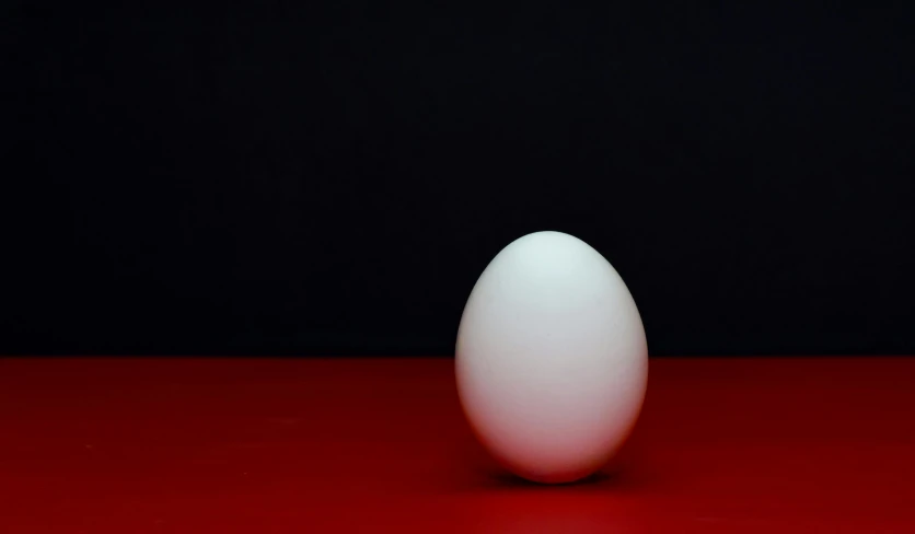 a small white egg is shown in front of a black background