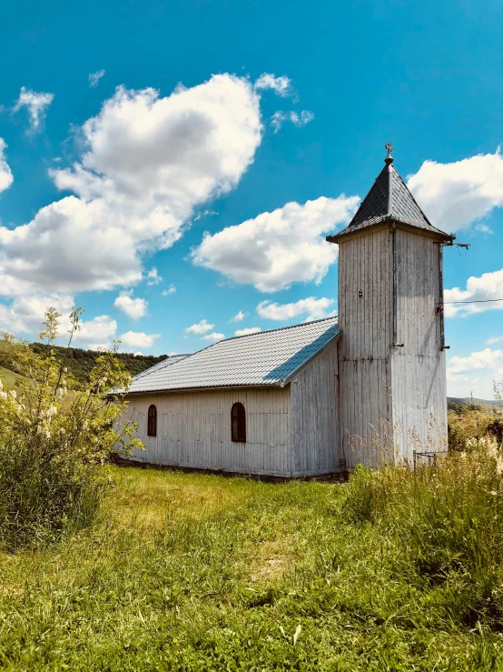 a small white church on a hill near the mountains