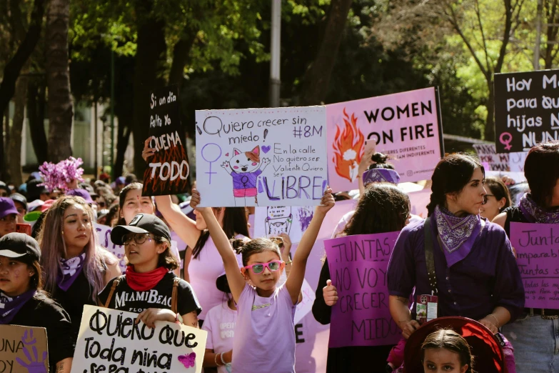 young women march through a park carrying signs that read women on fire