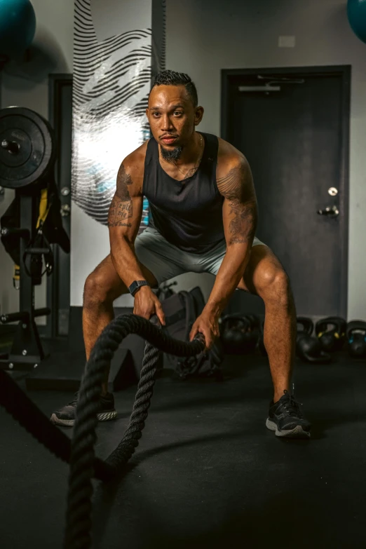 a man doing exercise with a rope and rubber apparatus