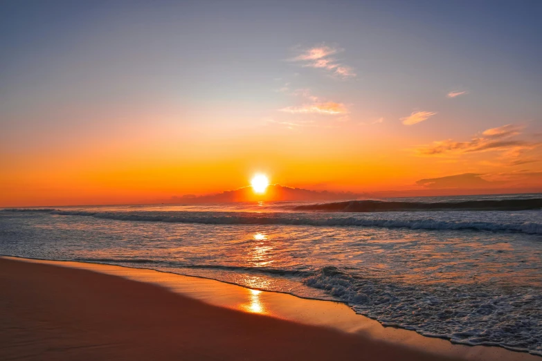 the sun setting over the ocean on a beach