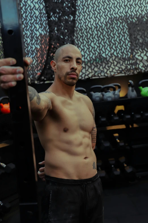 a man holding his phone up next to some gym equipment