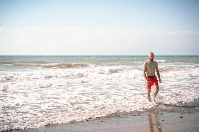 man walking along beach next to rough ocean