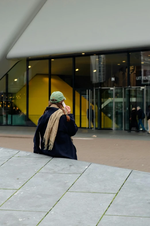 the person sits outside on the pavement using her cell phone