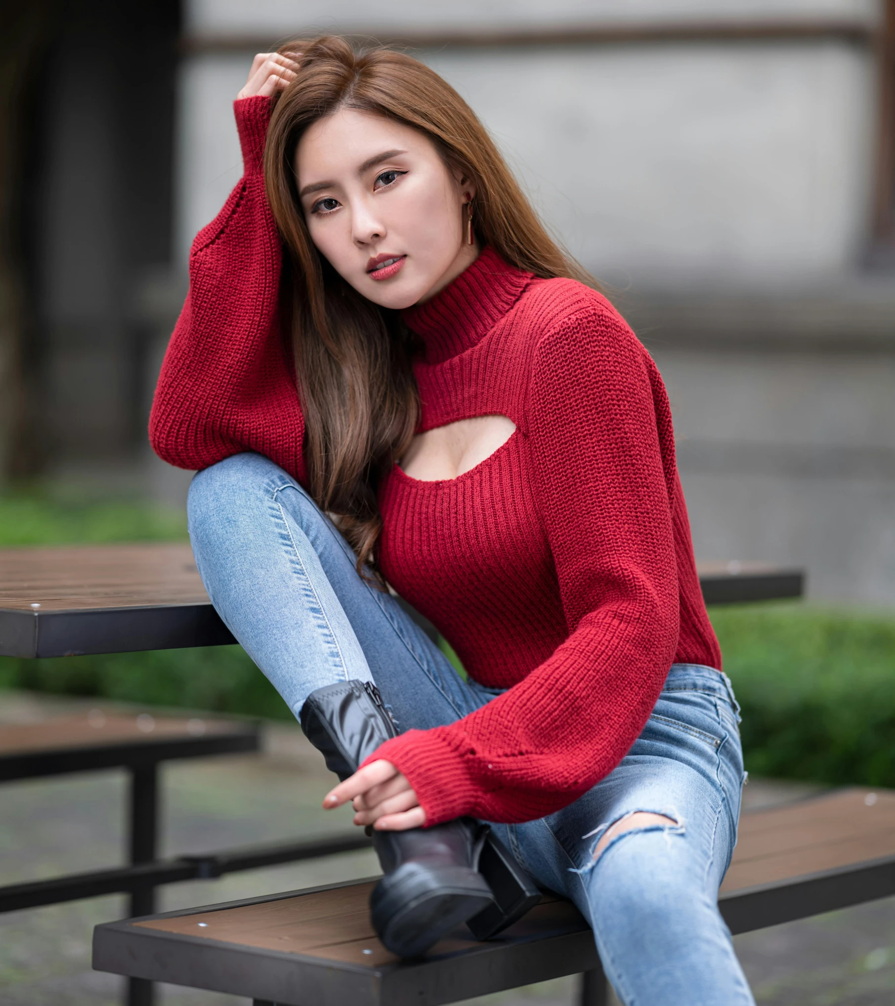 a woman sits on a bench wearing a red sweater