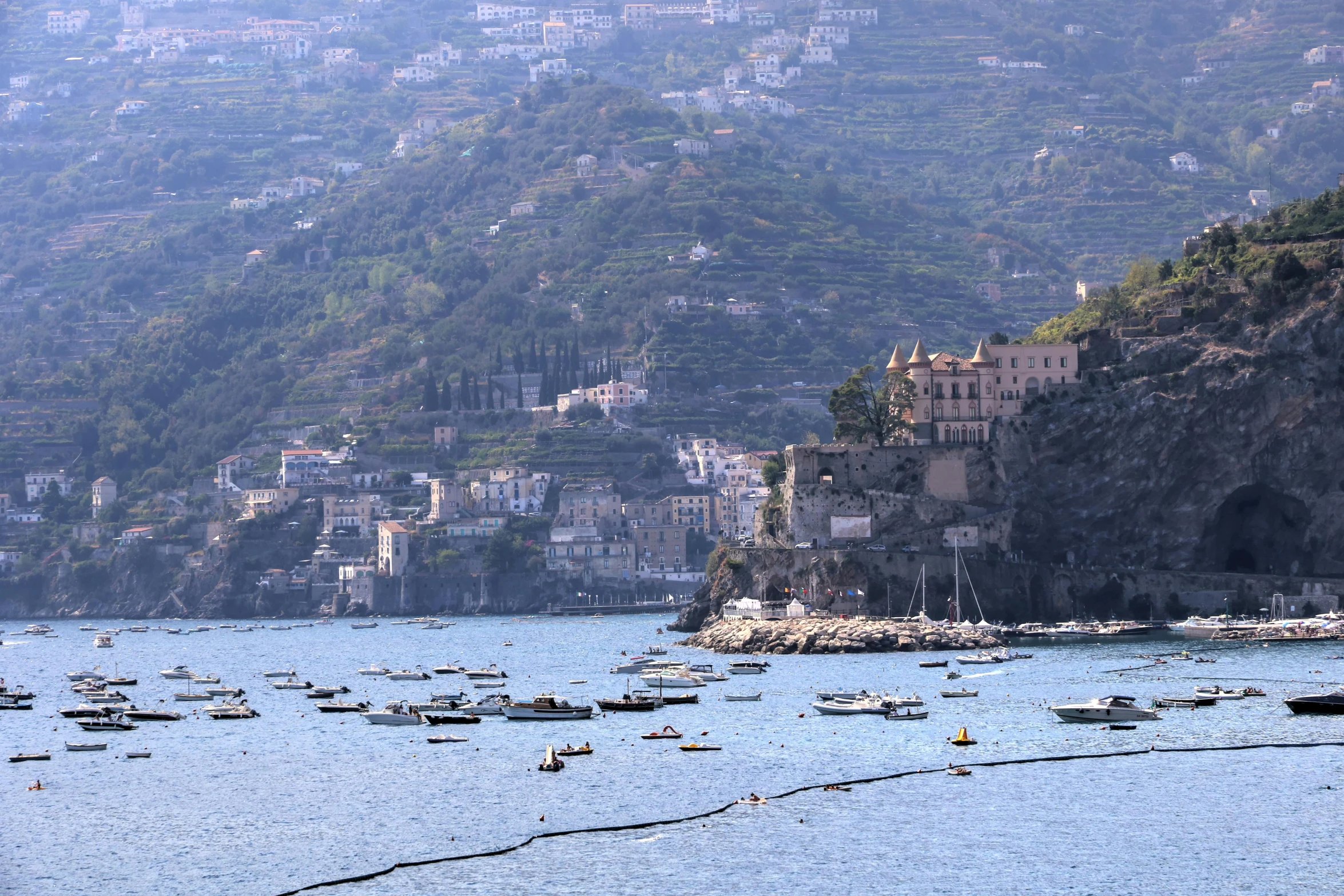 boats are in the water near a cliff with buildings