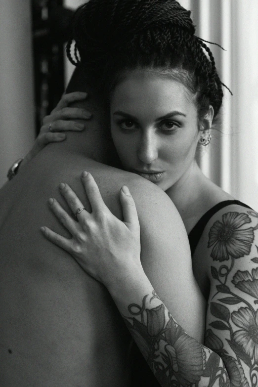 a person with tattoos hugging another persons back