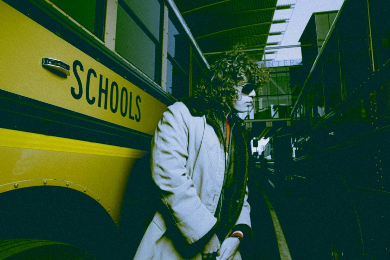 a person in white suit and sunglasses by a school bus