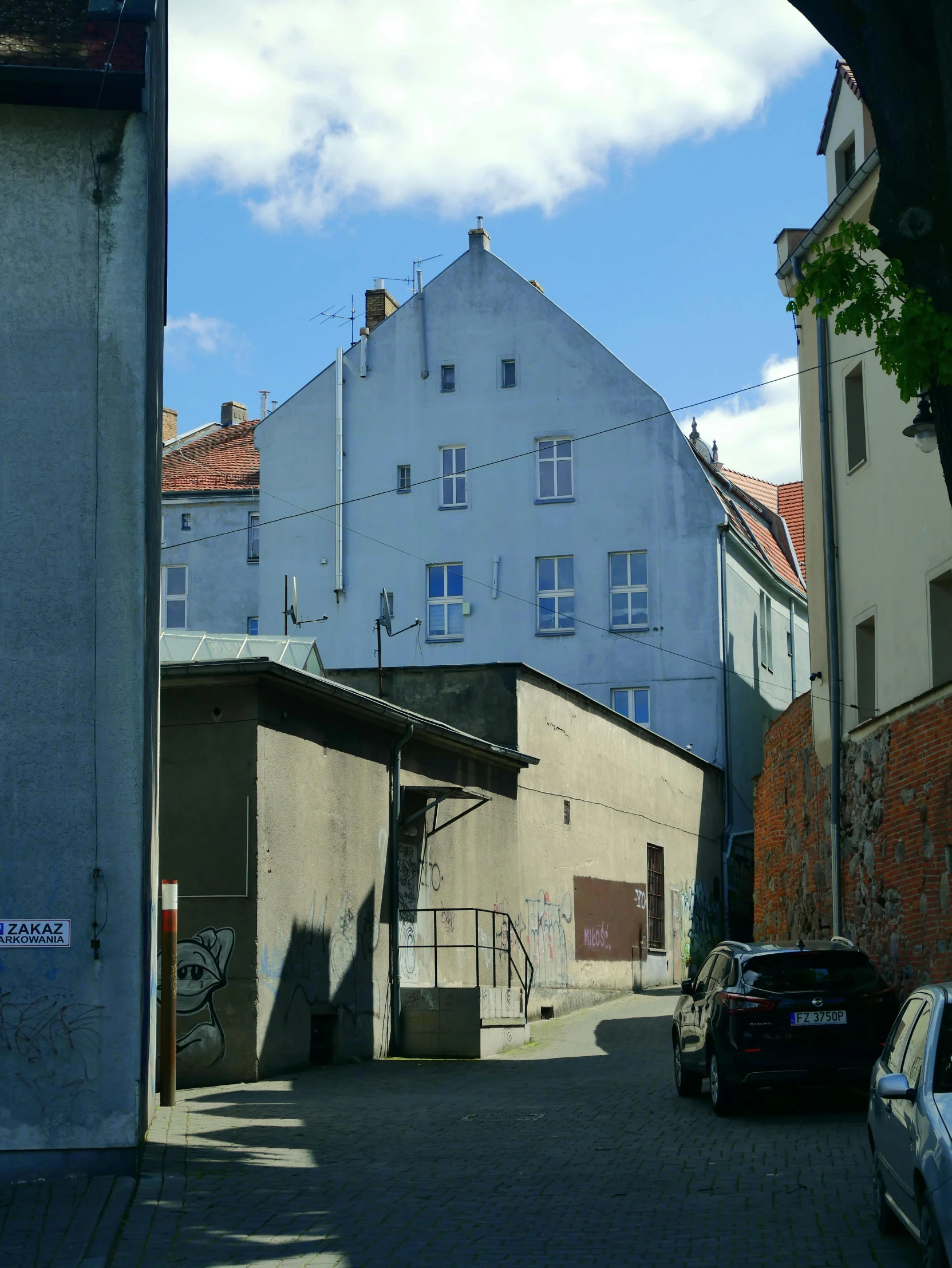 a white building with blue windows is surrounded by grey buildings