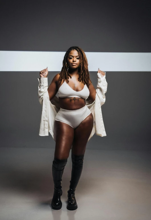 a black woman wearing underwear and thigh high boots poses for a po