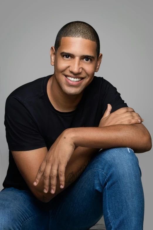 a man that is sitting down smiling at the camera