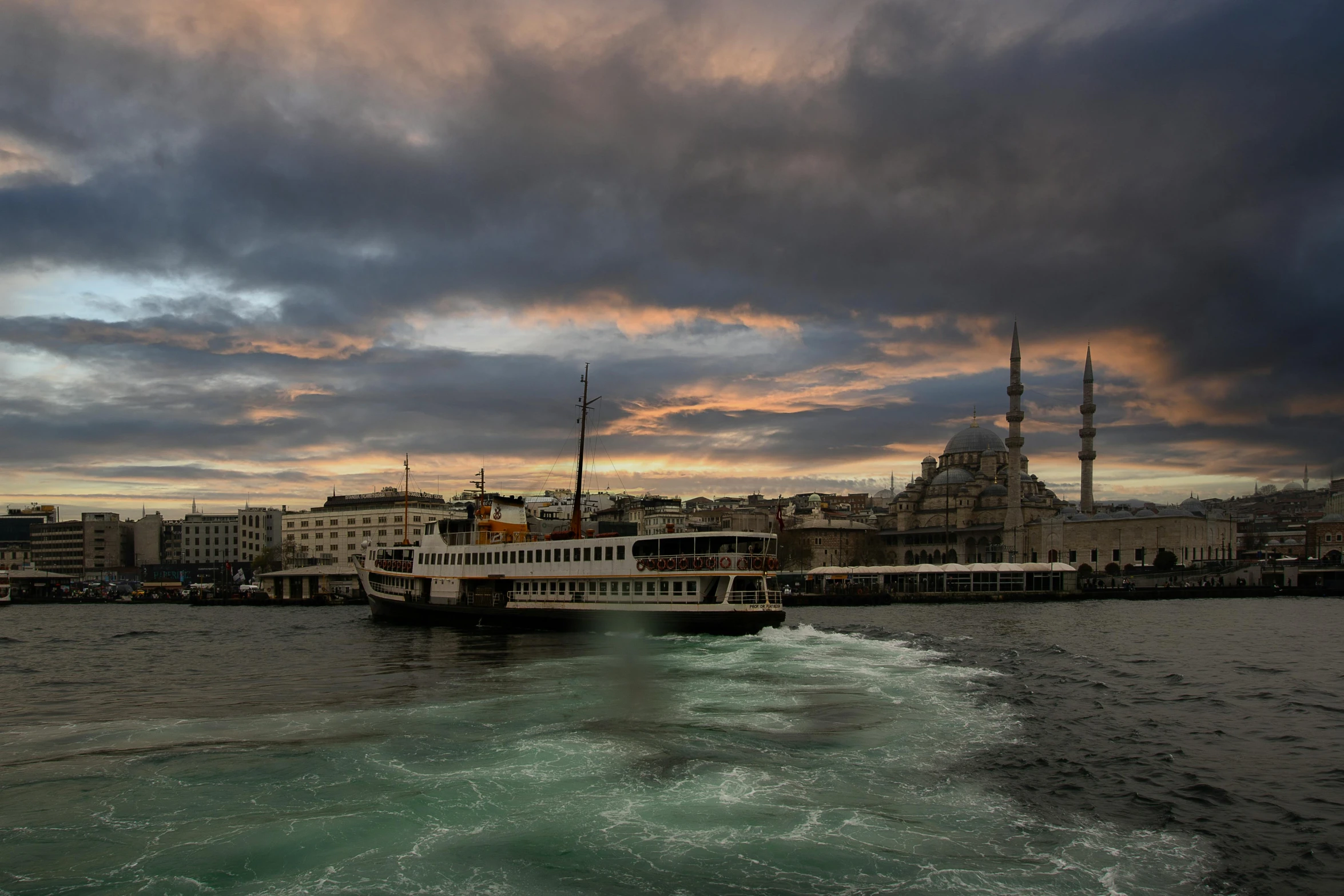 a large ferry boat in the middle of the ocean under stormy skies