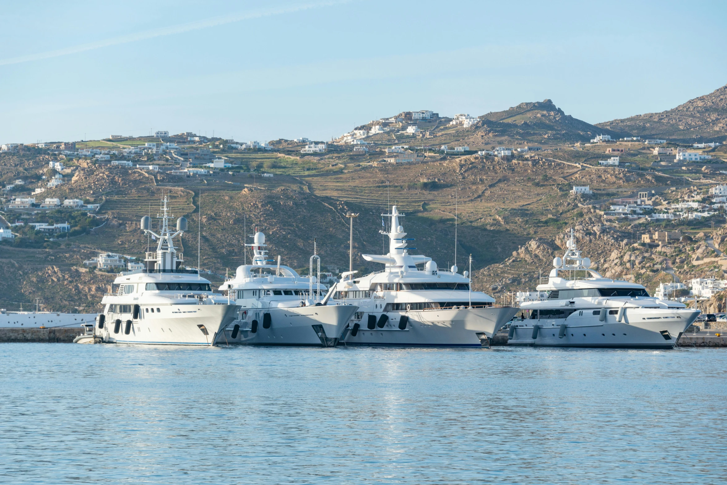 several boats docked at the shore in front of the mountains