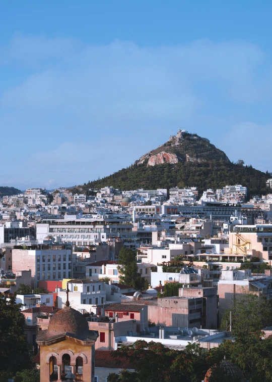 a tall city on top of a hill surrounded by trees