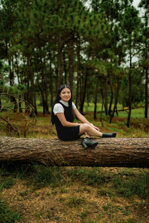 a woman sitting on top of a tree log in a park