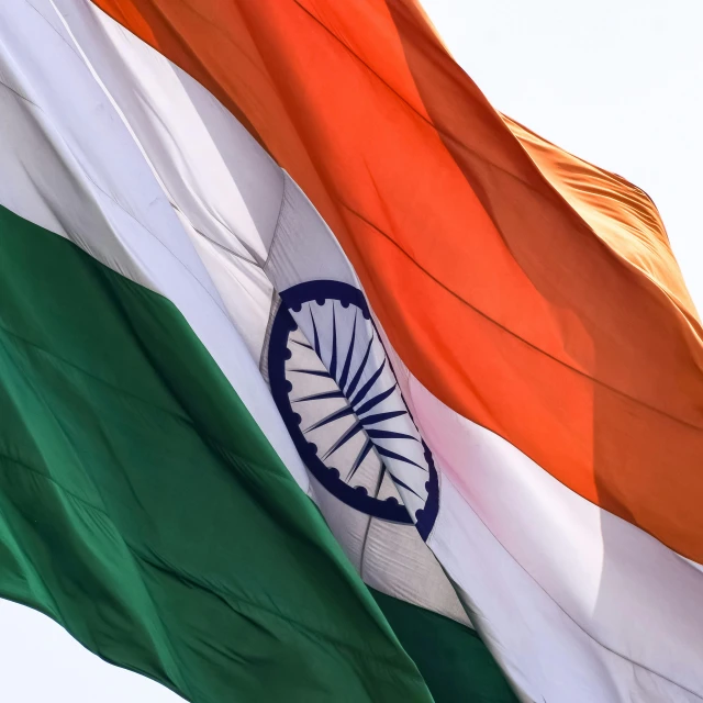 the indian flag flying in the wind with a blue sky in background