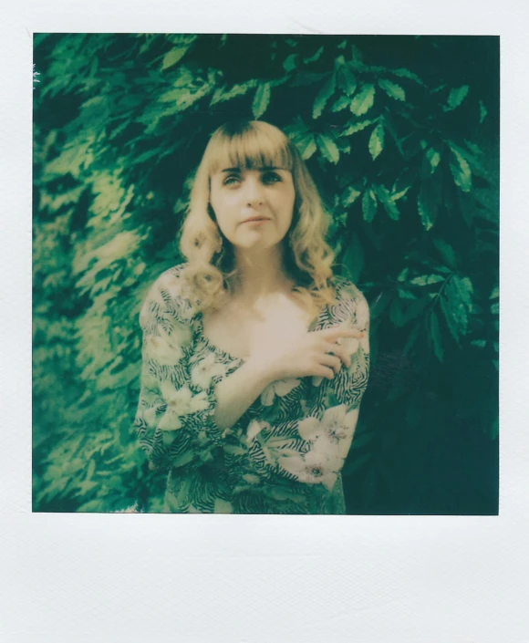 a woman is standing in front of trees and shrubs