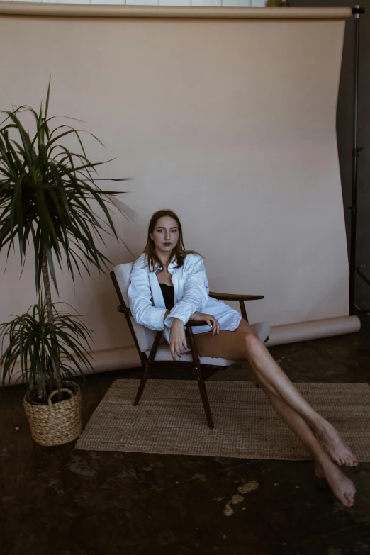 a woman sitting on a chair in front of a plant