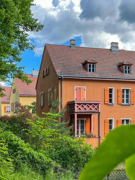 orange house with wooden stairs, with green tree and sky in the background