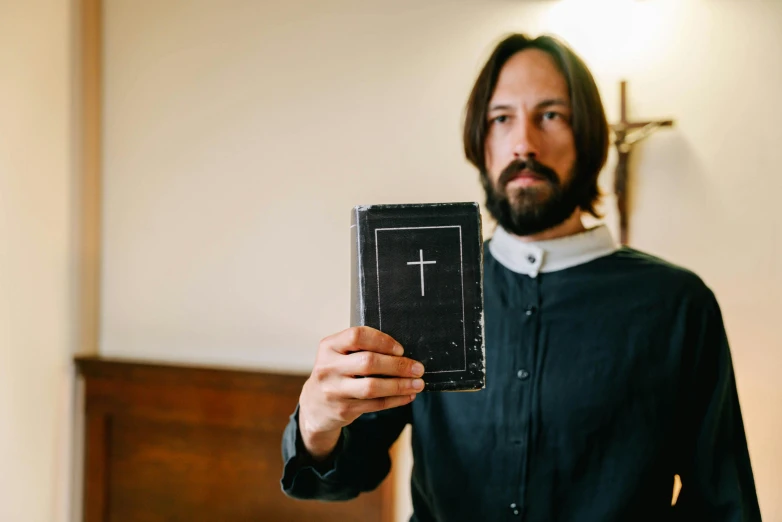 man showing a small chalkboard with a cross on it