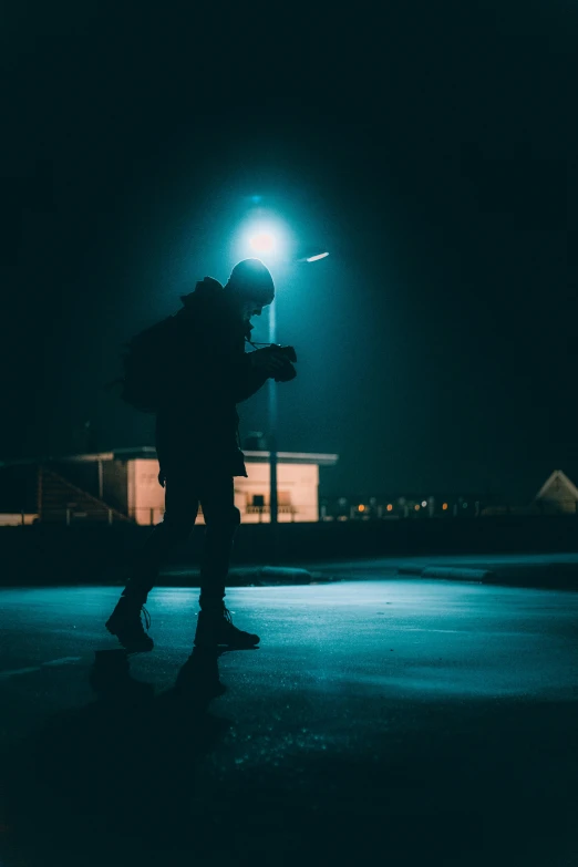the silhouette of a man holding a camera in front of a lit building at night