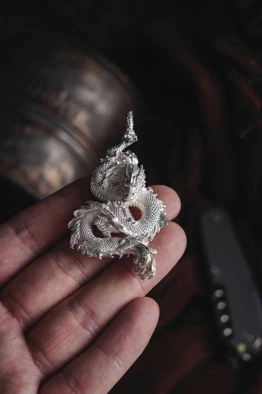 a hand holding an ornate silver ring in it's palm