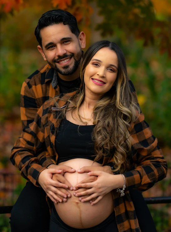 an attractive pregnant woman cuddles her husband's belly while they pose in a natural po