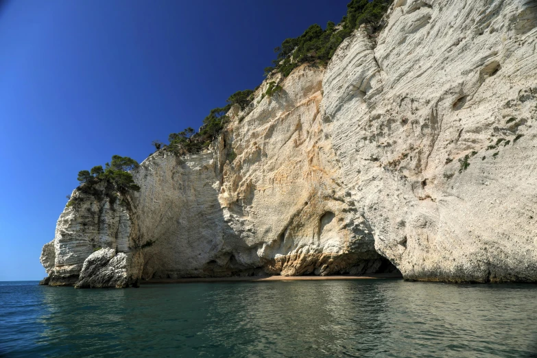 a boat that is sitting on the water near some cliffs