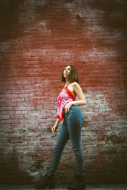 a young woman standing in front of a brick wall