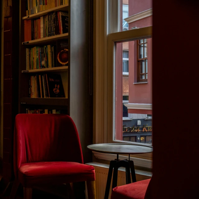 a red chair near a table by a bookcase