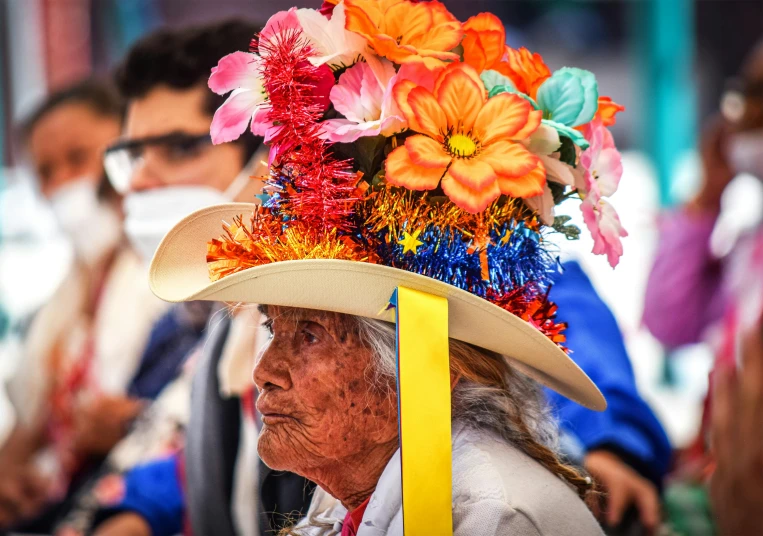 the elderly woman wears an elaborate flower hat