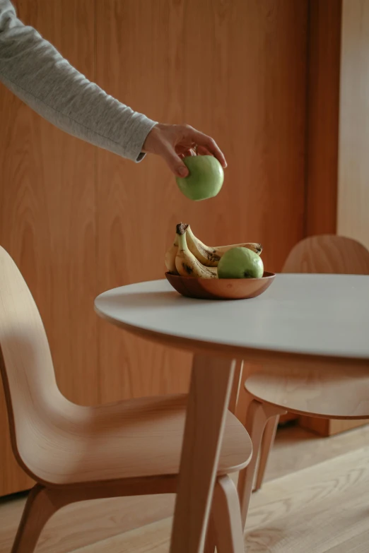 a person that is reaching for an apple on a table