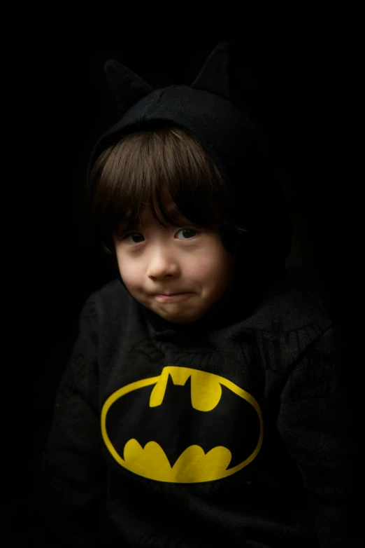 a young child with a batman t - shirt on and a hat on