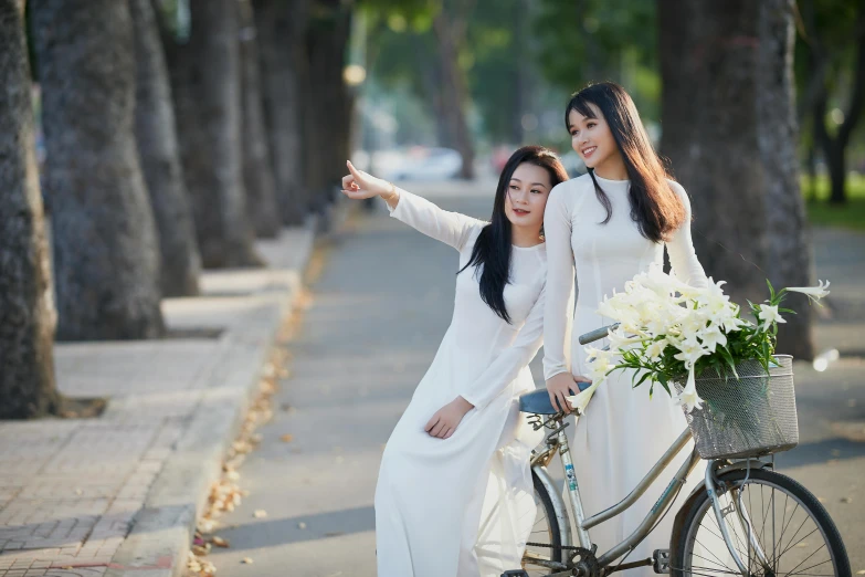 two girls with a bicycle smiling for the camera