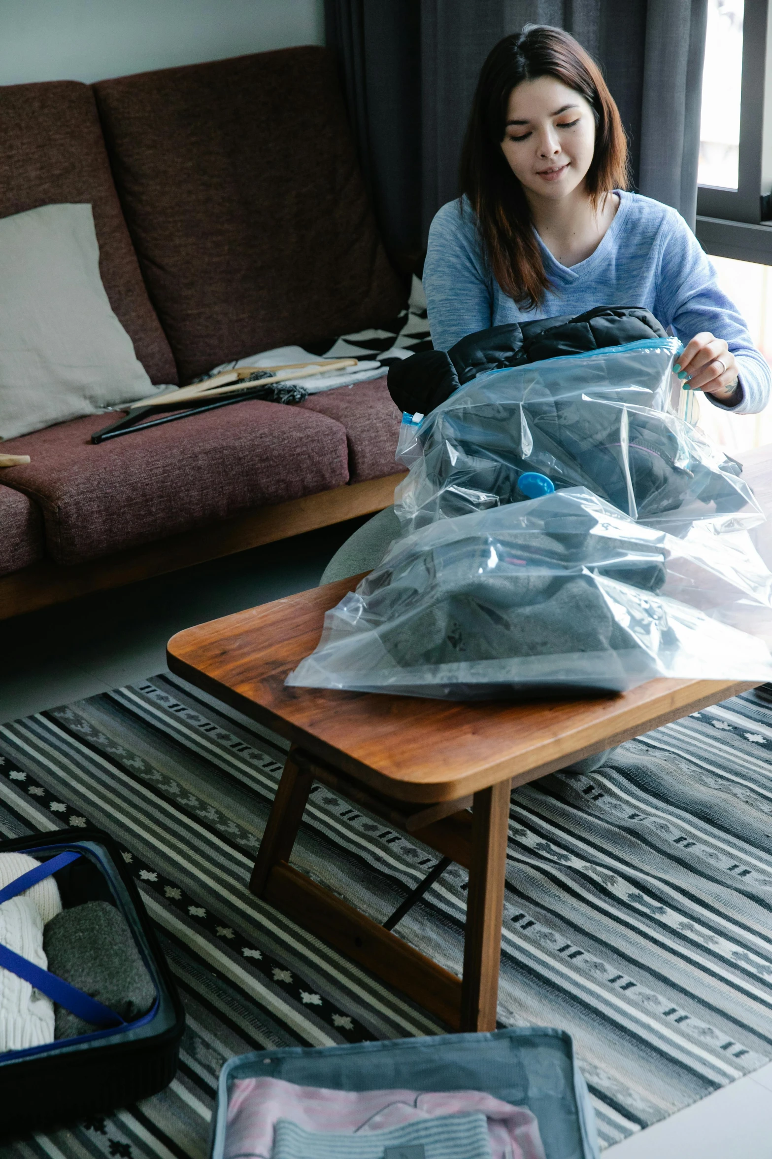 a woman packing clothing in a plastic bag