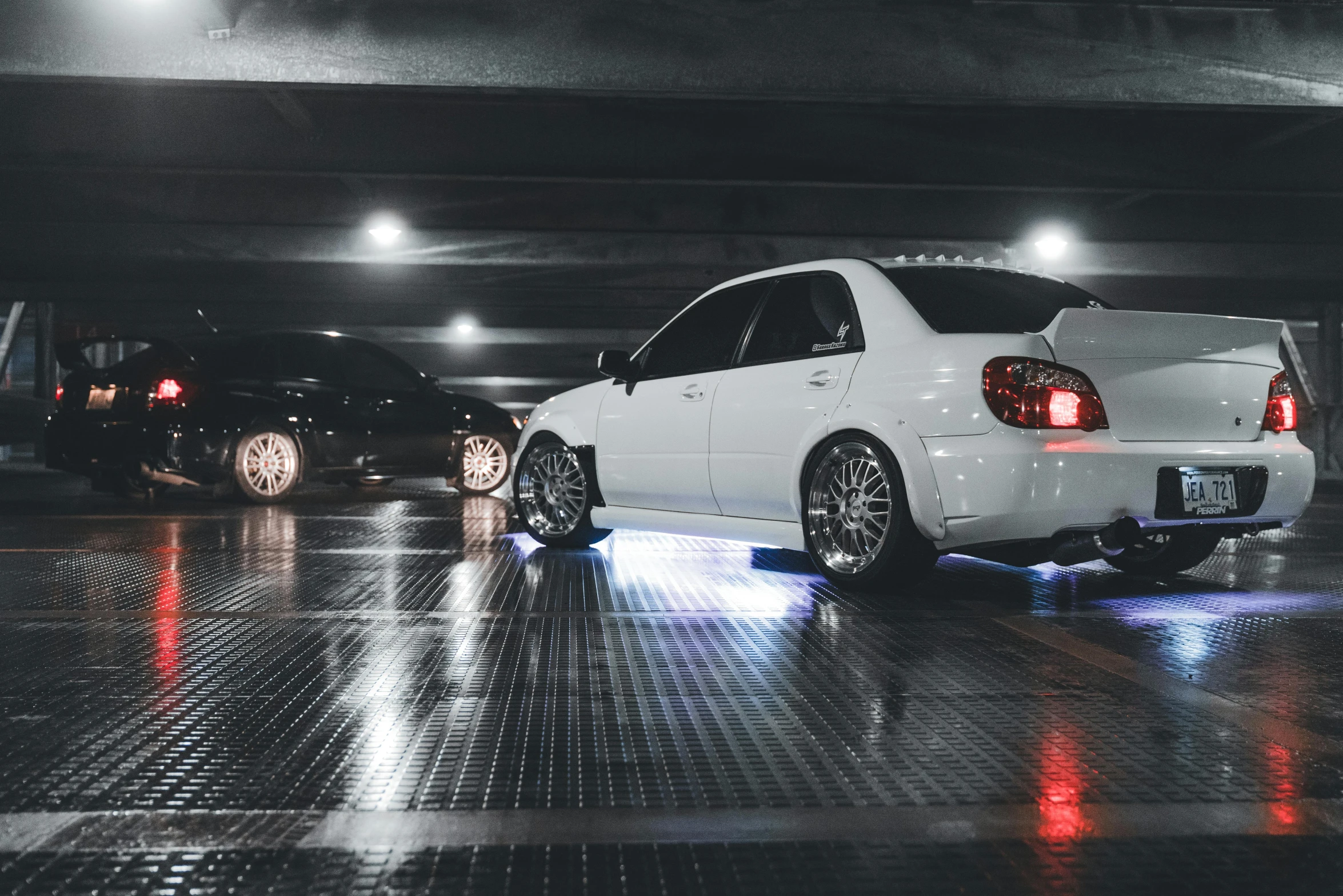 two white cars sit parked in an open parking garage