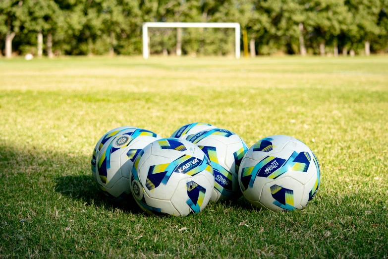 five soccer balls sitting in the grass on a field