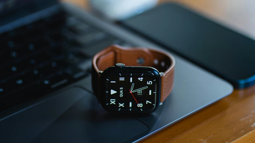 an apple watch sitting on top of a laptop keyboard