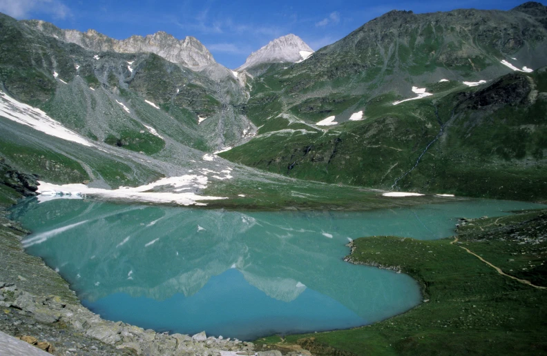 a mountain side with a lake in the middle and snow on it