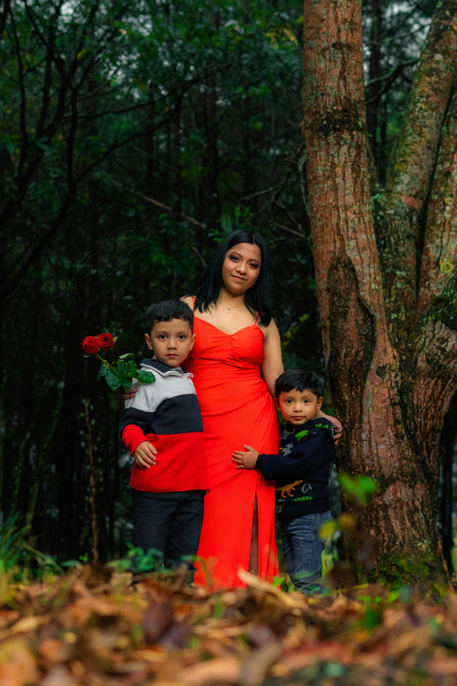 a woman in a red dress and two boys and tree