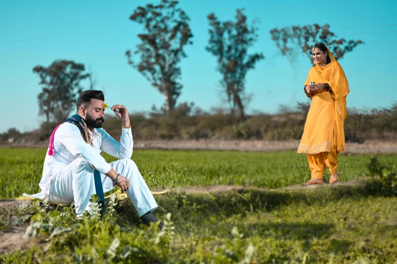 two people sitting down in the grass with drinks