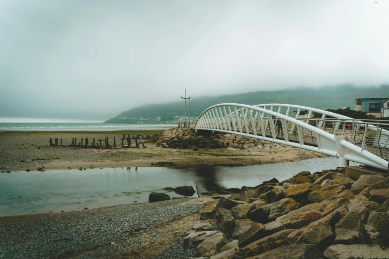 the white bridge crosses over rocks and water in front of houses