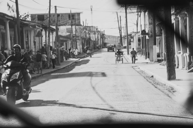 a motorcycle is driving down a street as people on bicycles watch