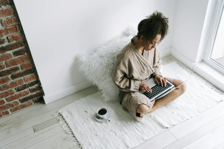 a woman on the floor is sitting on the floor and using her laptop