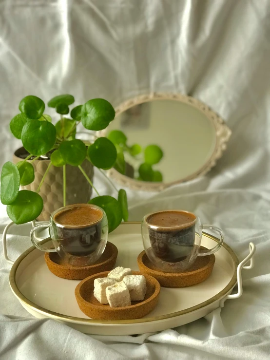 there are three cups on a tray beside a mirror