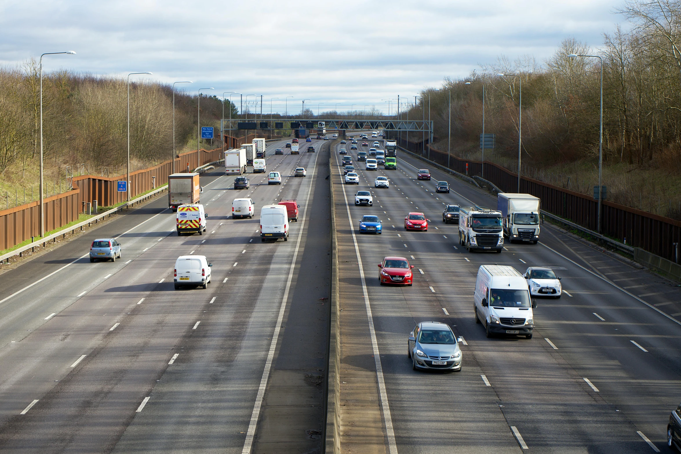 traffic on highway surrounded by gated fences and trees