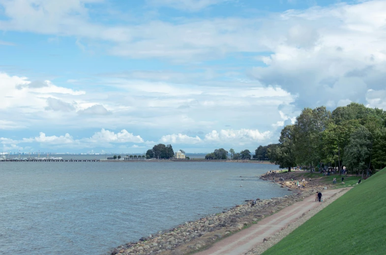 a large body of water next to a lush green field